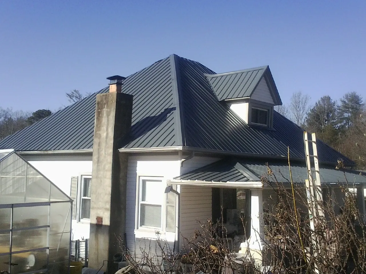 Dark blue standing seam metal roof on a white farmhouse with dormer — Slate & Tile Roof Repair by Roofing Brothers in Windber