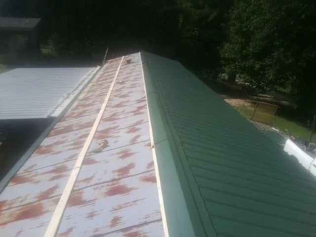 Old rusted panels beside newly installed green metal roofing — Wind Damage Roof Repair by Roofing Brothers in Windber