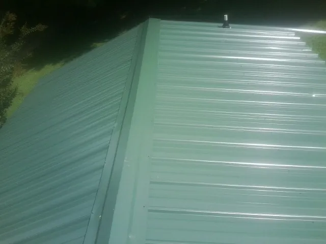 New green metal panels meeting at the ridge of a roof — Flat Roof Repair work by our crew in Windber