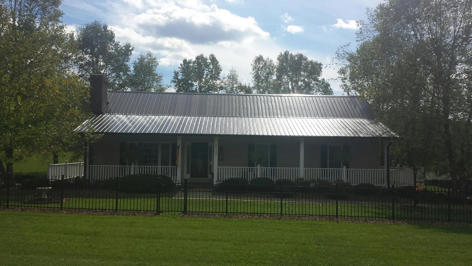 Gray metal roof on a brick ranch with a full width front porch — Gutter Guard Installation work by our crew in Windber