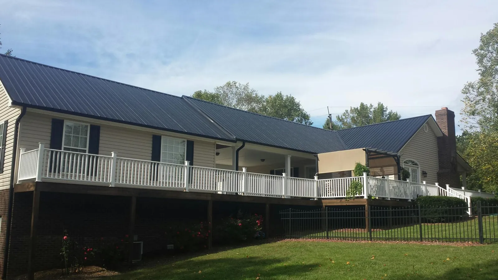 Black metal roof above a long white railed deck on a hillside home in Windber