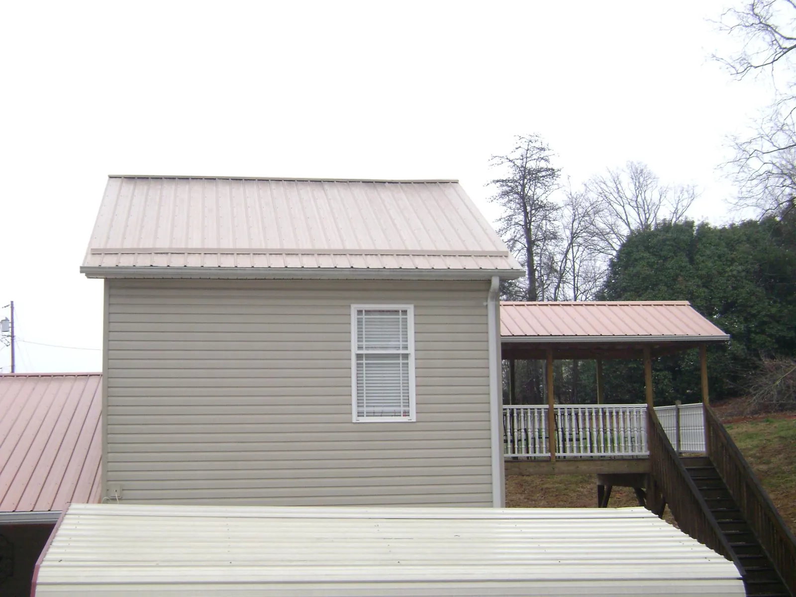 Tan metal roofs on a two story addition and attached porch, from a Roof Replacement job in Windber